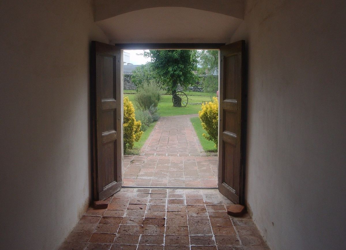 Puerta abierta que da a un patio con senda de ladrillo